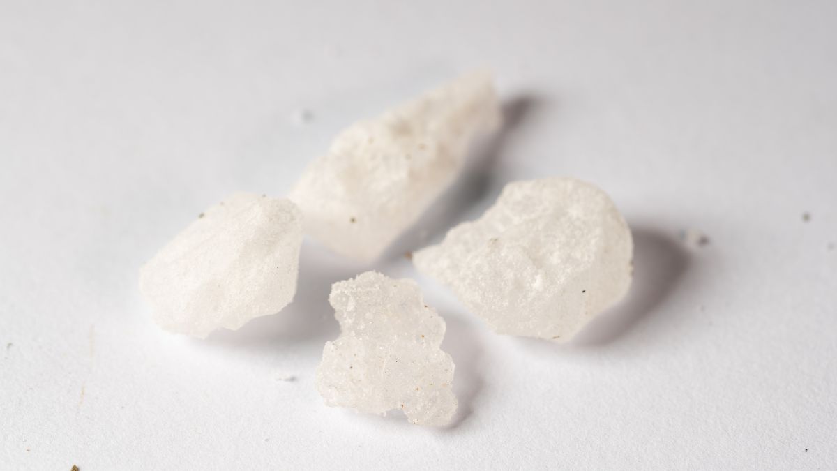 Fehér, kristályos nátrium-szulfát-dekahidrát darabok egy világos háttéren.