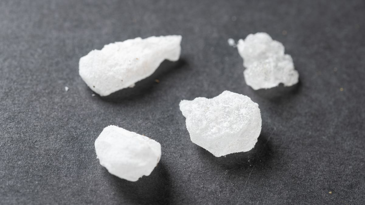 Néhány fehér, kristályos Glaubersó darab egy sötét háttéren.