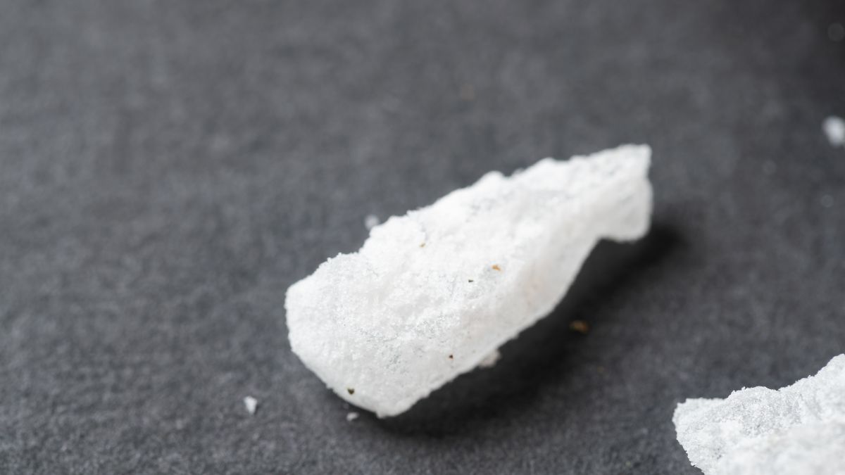 Fehér, kristályos Glaubersó darab egy sötét háttéren.